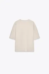 Camiseta color beige de corte amplio, cuello redondo y mangas cortas.