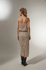 Falda midi dorada con lentejuelas y abertura lateral.