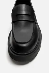 Mocasín de cuero color marrón oscuro, con antifaz y suela track de goma negra.