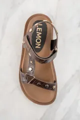 Sandalias marrones de cuero con suela gruesa y tachas doradas en forma de estrella y circulares.