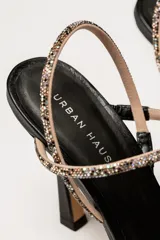 Sandalia de tacón negro con tiras cruzadas y detalles brillantes.
