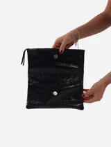 Sobre de fiesta negro charolado con cierre de solapa imantada y tira de cuero para sujetar a la muñeca.