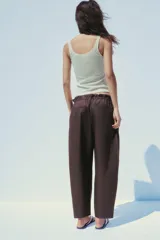 Pantalón marrón tipo barrel, de tiro medio con cintura elástica ajustable con lazada, bolsillos laterales y falsos bolsillos de vivo en la espalda.