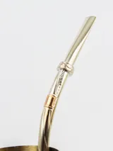 Bombilla de metal plateado con detalles dorados y diseño labrado.