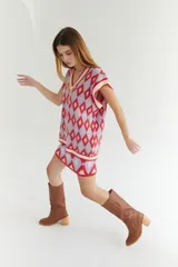 Chaleco tejido de lana con patrón de rombos en tonos lila, rojo y beige, con cuello en V y ribetes en color crema. Diseño oversize.