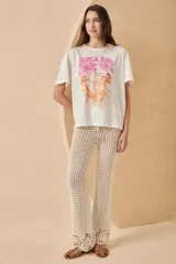 Remera blanca de algodón con estampado de un tucán, palmeras y la frase 'Tropical Bliss' en tonos naranja y rosa.