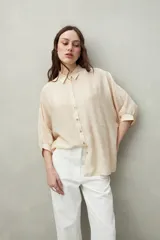 Camisa celeste de calce relajado con cuello clásico, mangas tres cuartos amplias y botones nacarados.