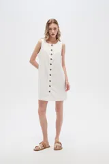 Vestido blanco de lino, corte entallado, con botones frontales, cuello a la base y breteles anchos.