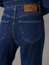 Pantalón de jean azul oscuro, de tiro alto, corte bootcut, cinco bolsillos y cierre con cremallera.