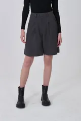 Bermuda de poliéster color gris oscuro, con pinzas frontales y corte holgado. Presenta un calce a media pierna.