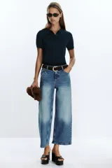 Pantalón de jean azul de corte culotte, tiro alto, pernera ancha y corta. Incluye cinturón marrón de gamuza con hebilla metálica.