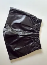 Short negro de cuero sintético con cintura elastizada y bolsillos laterales.
