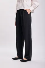 Pantalón de vestir negro, de corte carrot, con bolsillos laterales y traseros.