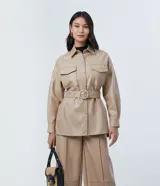 Campera de poliuretano (PU) color beige, con cuello camisa, cierre frontal de botones y dos bolsillos con solapa en el pecho. Incluye un cinturón ajustable con hebilla redonda forrada al tono.