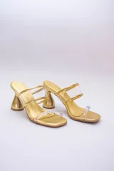 Sandalias doradas con tiras transparentes y taco geométrico.
