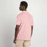 Remera polo de piqué color salmón con cuello y mangas con ribete blanco.