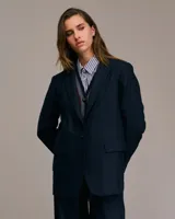 Blazer azul de corte medio largo, con cuello italiano, solapa de muesca, cierre frontal con un botón y bolsillos con solapa.