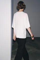 Remera blanca de punto liso, corte amplio, cuello redondo y manga corta.
