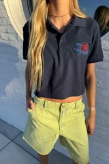 Remera corta de algodón color azul marino, con cuello tipo polo y bordado de una rosa en el pecho.