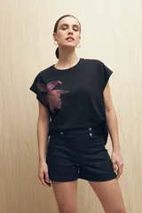 Remera blanca de manga corta con estampado de una flor color durazno en el frente.