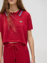 Chomba corta color rojo, con cuello camisero con rayas celestes y negras, logo bordado en el pecho y mangas cortas.