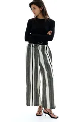 Pantalón palazzo de punto con textura a rayas verticales en blanco y negro. Tiene tiro alto, piernas rectas, elástico en la cintura y cordón para ajustar.