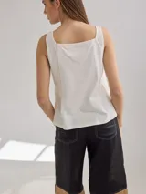 Musculosa color verde claro de lino en el frente y algodón en la espalda, con breteles anchos y escote cuadrado. Presenta detalle de pequeñas perforaciones verticales en el frente.