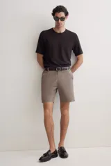 Short color marrón claro, de corte recto y largo a la rodilla. Presenta cintura con elástico en los laterales, cierre con botón, bolsillos al bies y bolsillos traseros ribeteados con botón.