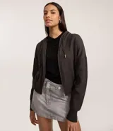 Campera corta de mujer con capucha ajustable con cordón, cierre frontal de cremallera y puños y bajo ajustados. Confeccionada en tejido de punto.