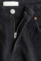 Pantalón jean negro de tiro alto, corte ancho y recto, con cinco bolsillos y cierre con botón.