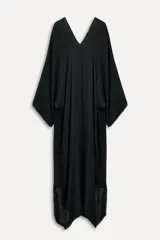 Vestido tipo capa color negro confeccionado en hilatura de viscosa, con escote pico, manga corta y bajo asimétrico desflecado.