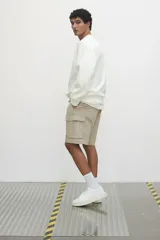Short color beige de tejido grueso de algodón, con corte estándar, cintura elástica con cordón ajustable, bolsillos al bies y bolsillos de solapa con cierre autoadherente en las piernas y atrás.