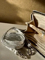 Billetera grande de cuero color verde oliva con correa de hombro desmontable. Tiene espacio para tarjetas, billetes, documentos y un bolsillo con cierre.