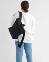 Mochila acolchada color ladrillo con cierre superior enrollable, correas ajustables y logo estampado en blanco.