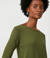 Suéter de punto color verde, con cuello barco, mangas largas y textura acanalada.