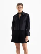 Camisa blanca de poplin de algodón con fit cómodo y largo que cubre hasta debajo de la cintura. Presenta botones ocultos en cartera y puños, y punteras de níquel en el cuello.