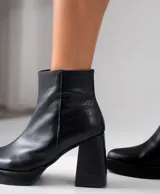 Bota corta negra de cuero vacuno, con taco de madera de 9 cm y plataforma delantera de 2 cm.