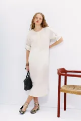 Vestido midi tipo túnica color crudo, de calce recto, con escote redondo con botones y bordados en hilo en el frente, sisas y ruedo.