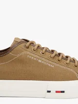 Zapatillas bajas de lona color marrón, con cordones y suela de goma vulcanizada color blanco. Presentan costuras contrastantes en blanco y detalles distintivos de la marca en la entresuela.