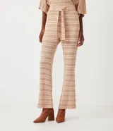 Pantalón largo de tejido de punto con rayas horizontales en tonos beige y marrón claro. El pantalón es de corte flare, con cintura alta y lazo para ajustar.