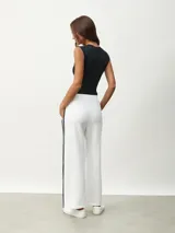 Pantalón blanco de corte ancho con una fina línea negra vertical en los laterales.