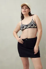 Falda corta de denim color negro, con corte recto y costuras verticales resaltadas. Presenta tiro alto con botón y cierre frontal, y bolsillos diagonales delanteros.