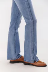 Jean de corte semi oxford con tiro medio, confeccionado en denim de lavado claro. Presenta costuras verticales decorativas en el frente y un detalle de costura en la botamanga que amplía la silueta.