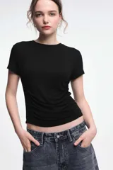 Remera negra de corte ajustado, mangas cortas y cuello redondo. Presenta frunces laterales que realzan la figura.