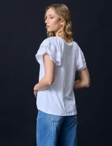 Blusa blanca texturada de poliéster, rayón y elastano, con mangas cortas con volados en capas y aplique de puntilla.