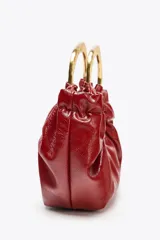 Bolso de mano fruncido color rojo con doble asa metálica dorada. Incluye bolsillo interior con cierre y asa bandolera extraíble.
