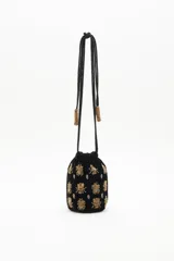 Cartera tipo bombonera negra de terciopelo con bordado de lentejuelas y canutillos dorados con forma de insectos. Tiene cordón de ajuste con borlas de canutillos dorados y correa de mano.