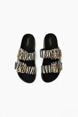 Sandalias planas con estampado de cebra, suela de corcho y hebillas doradas.