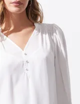 Blusa blanca de gasa marca Tahari, con escote en V, apliques de botones y detalle de punto smock en hombros y puños. Incluye musculosa a tono.