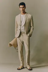 Blazer color beige de corte slim fit, con solapas de muesca finas, botonadura sencilla con cierre de dos botones, bolsillo superior, bolsillos delanteros con solapa, tres bolsillos interiores, botones decorativos en los puños y abertura atrás.